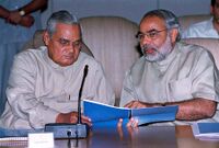 Modi and former Prime Minister Vajpayee looking at a blue-covered report